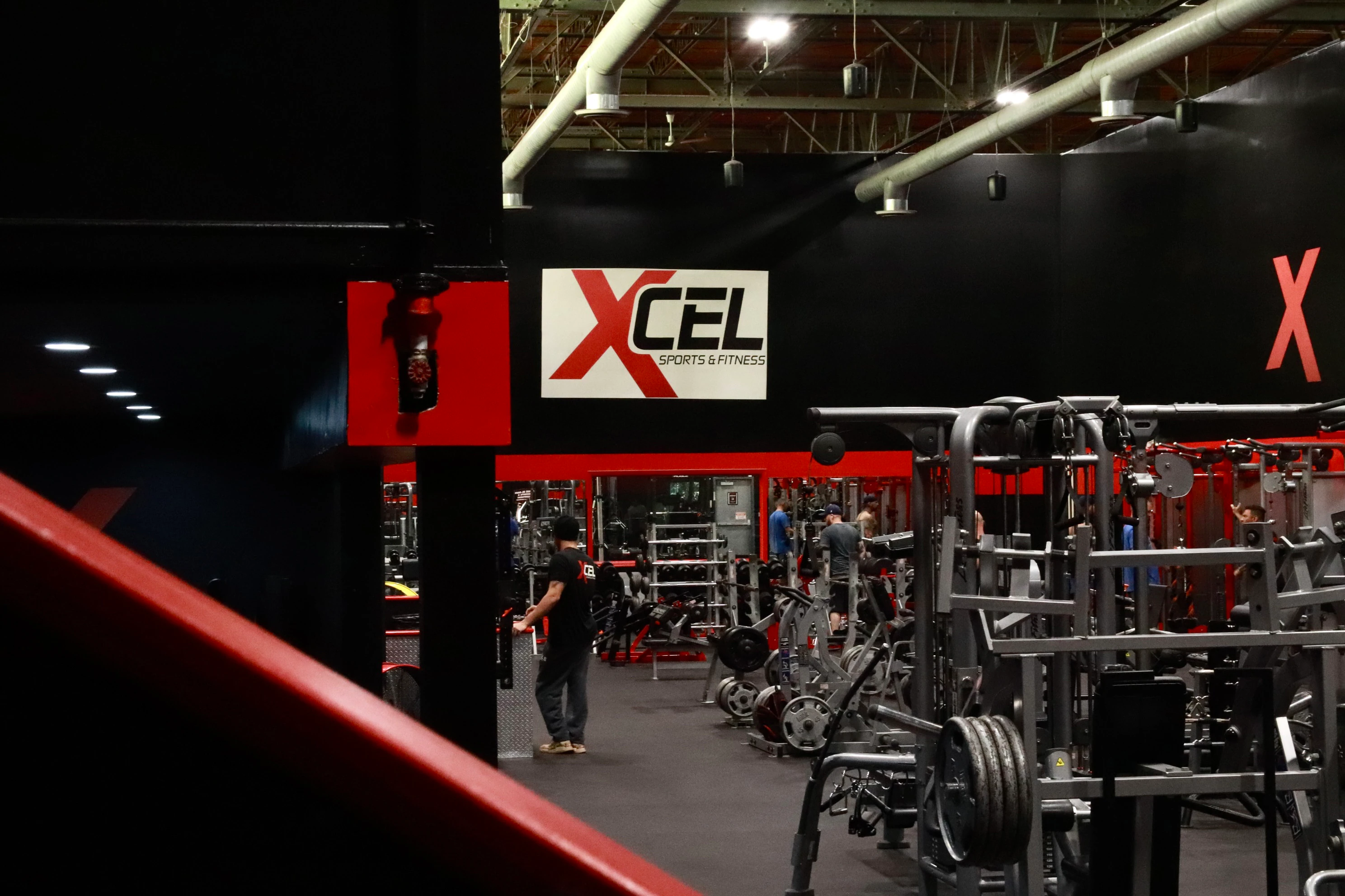 Members training on the strength floor below the XCEL sign at XCEL Sports & Fitness, a gym in Fairfield, NJ