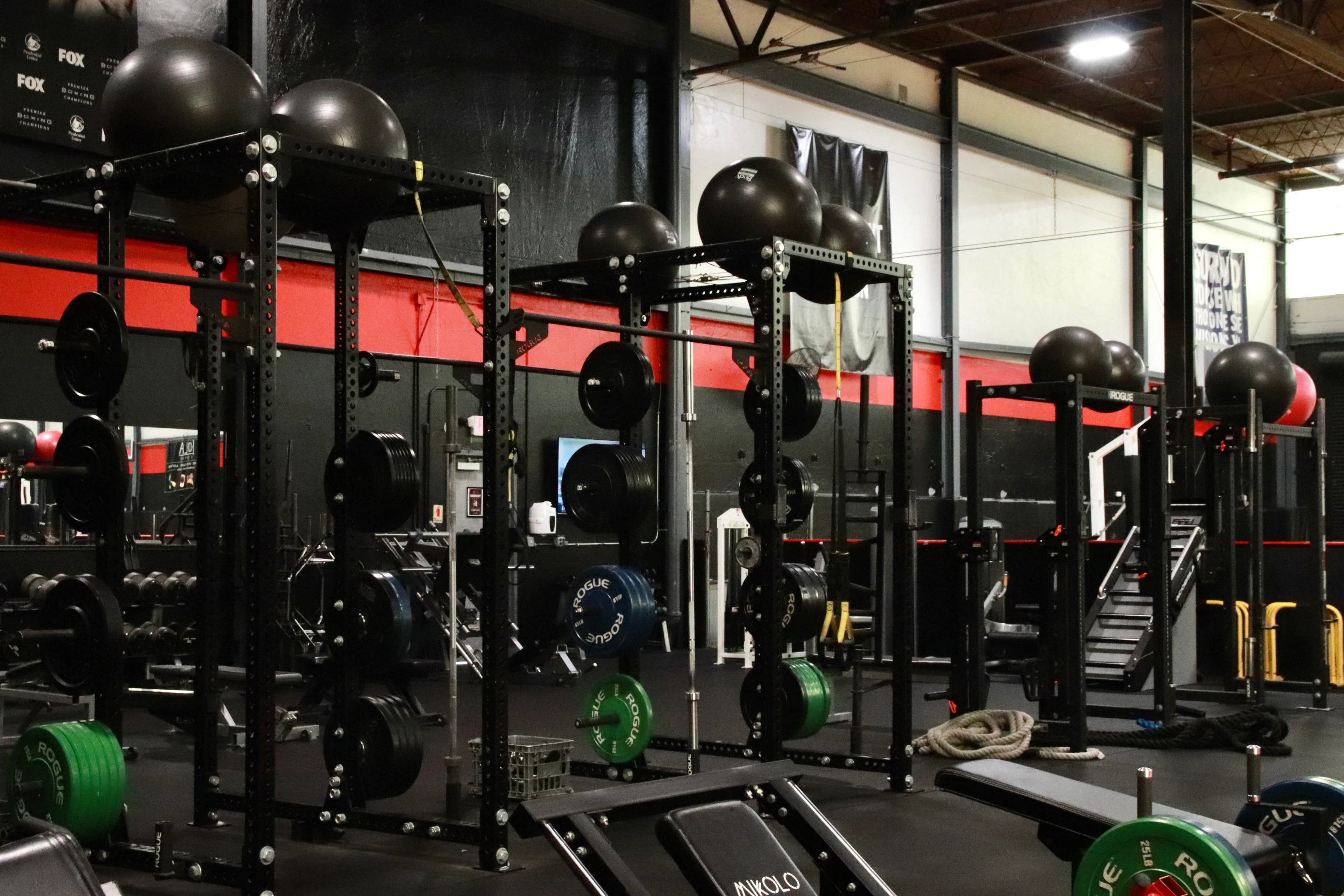 Squat rigs with bumper plates and slam balls in the performance area at XCEL Sports & Fitness in Fairfield, NJ